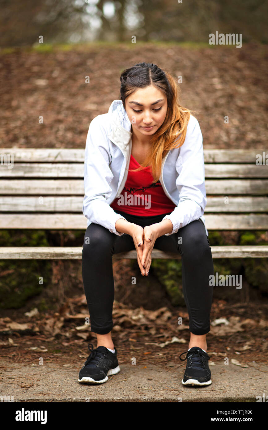 Thoughtful woman sitting on bench at park Stock Photo