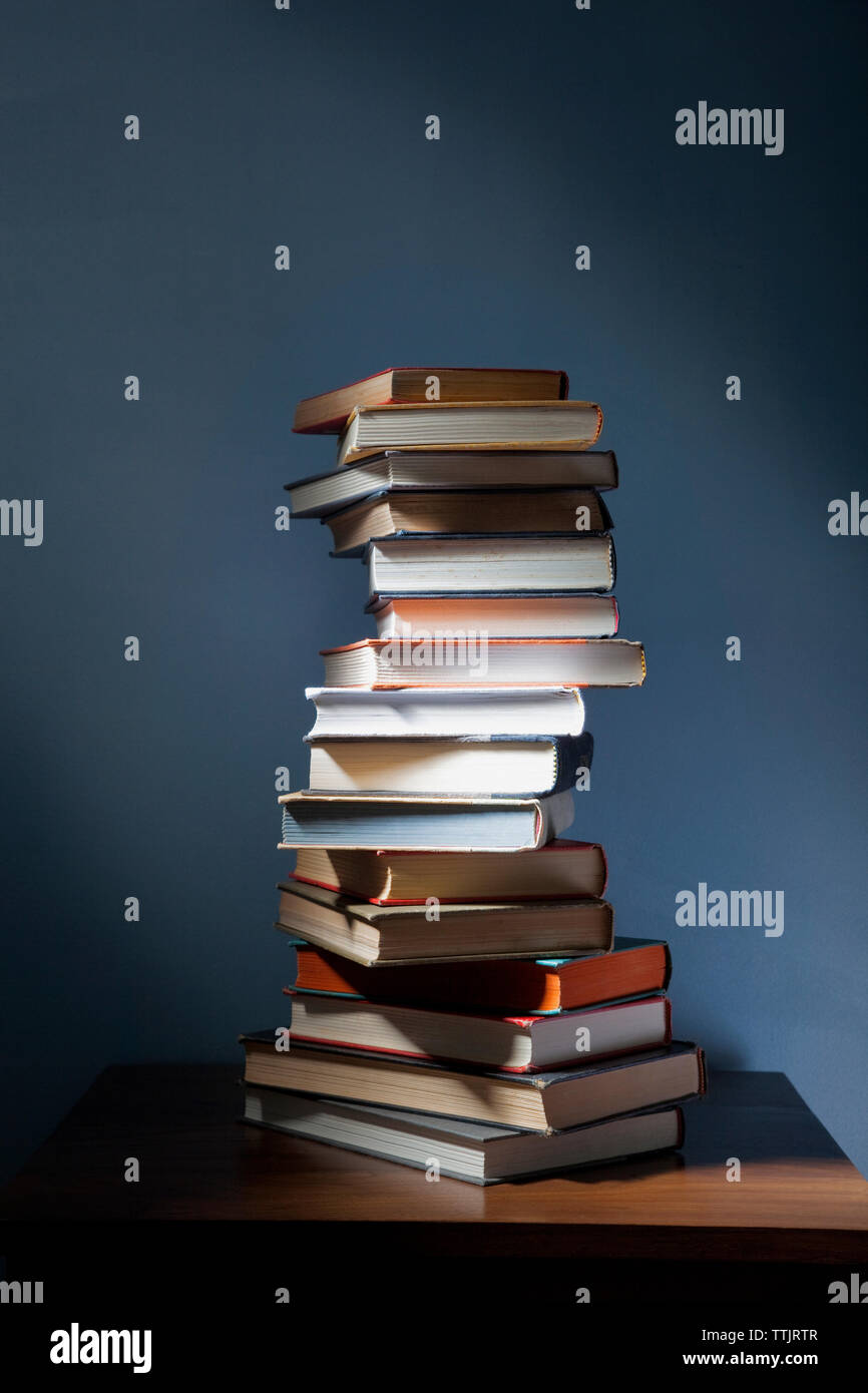 Stack of books on wooden table in darkroom Stock Photo