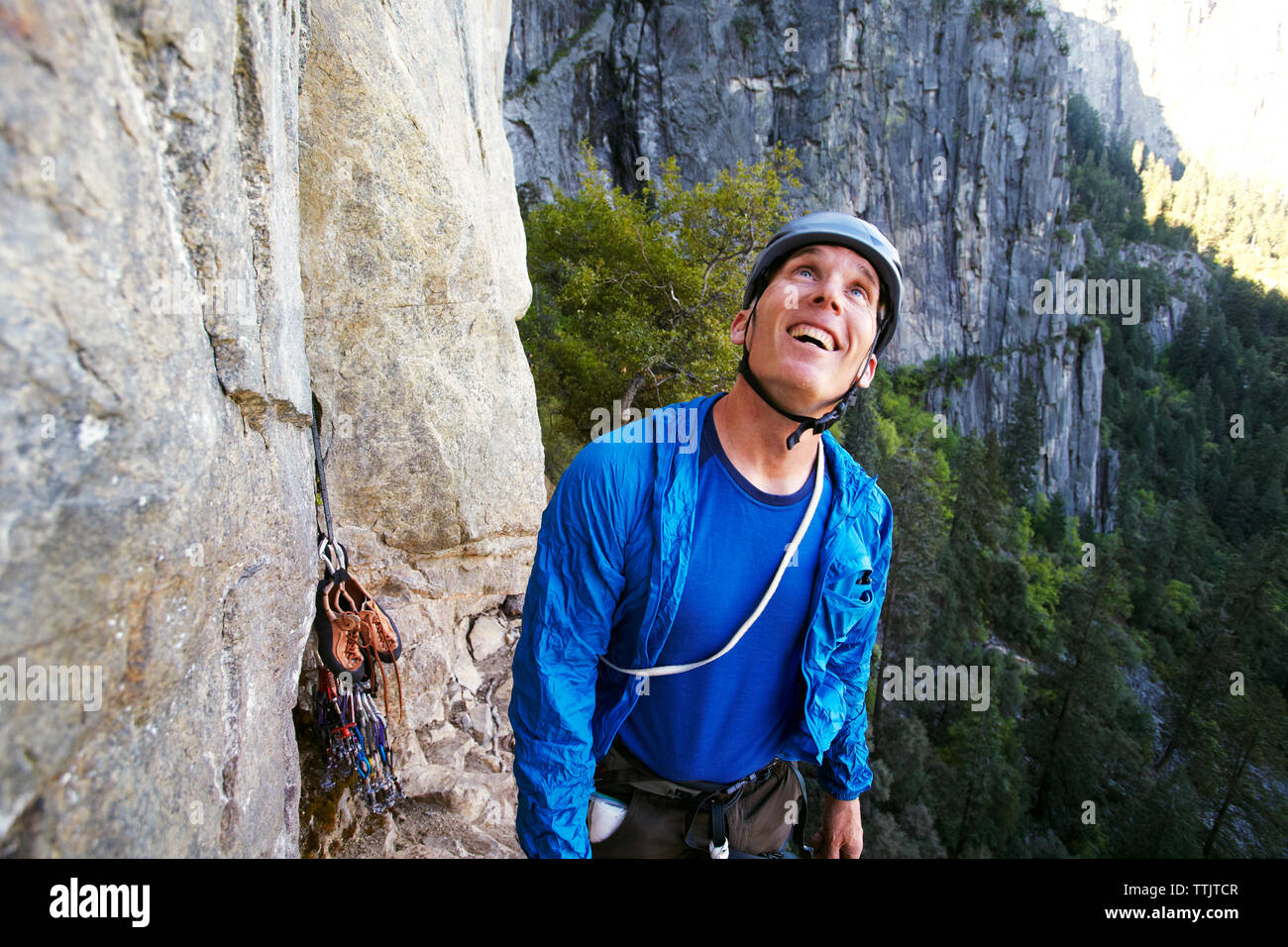 Happy man looking up while standing by rock formation against mountain Stock Photo