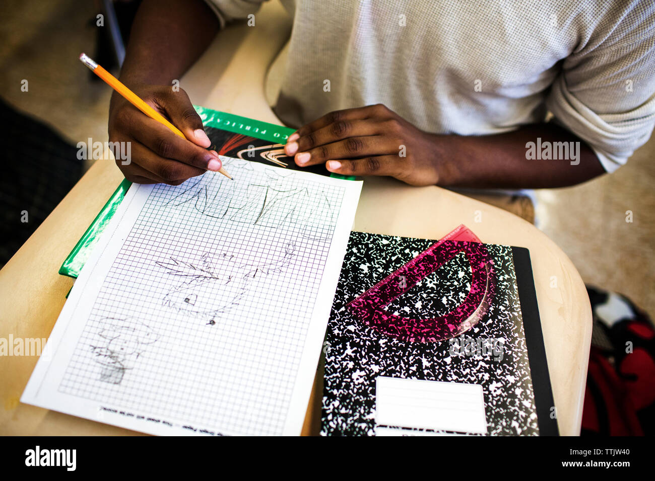 High angle view of teenage boy drawing on graph paper in classroom Stock Photo