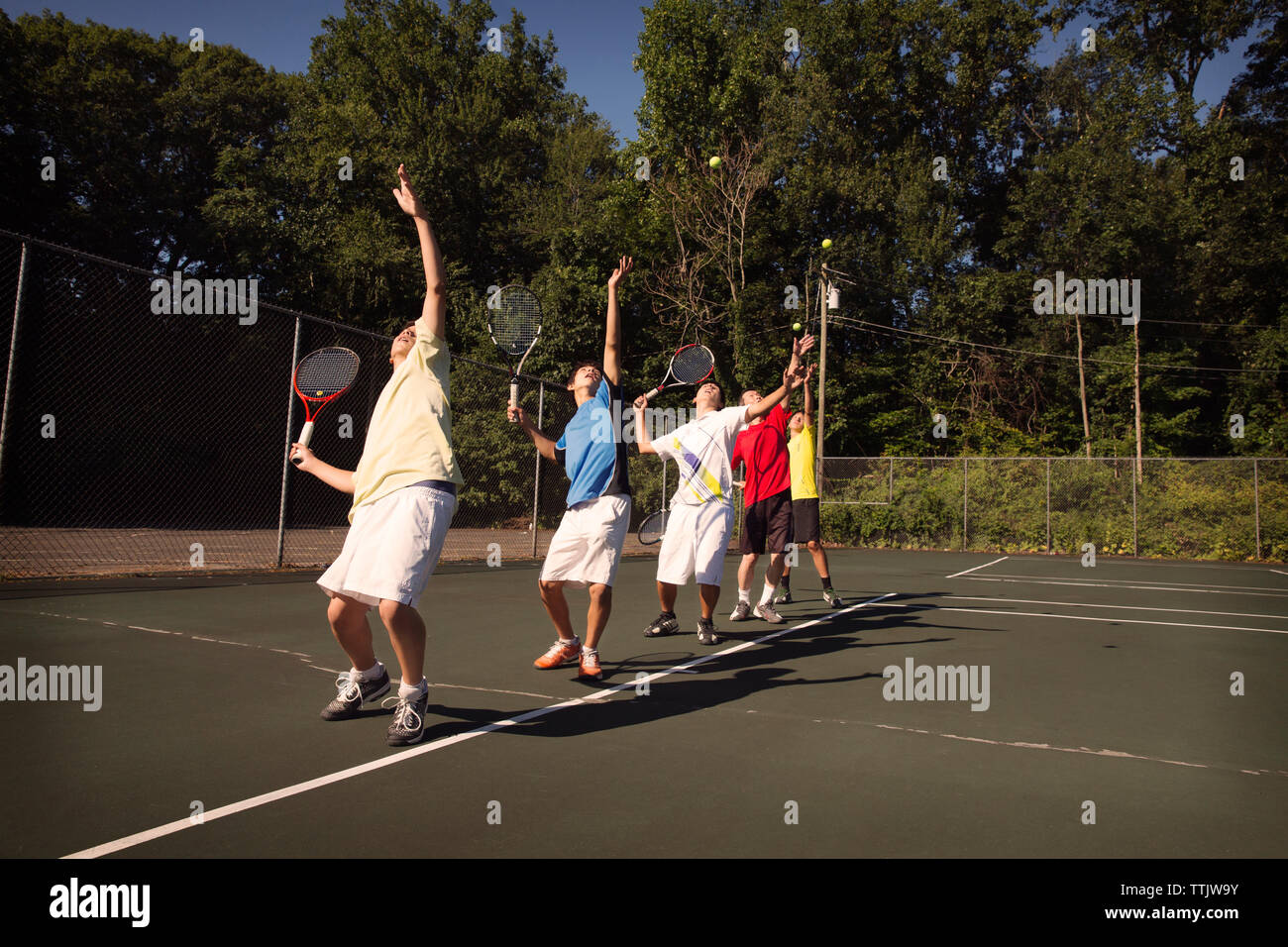 Players standing in row playing tennis at court Stock Photo