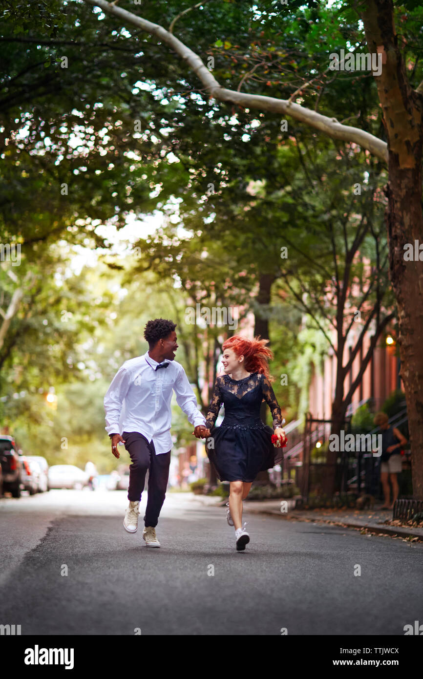 Happy couple holding hands and running on street Stock Photo - Alamy