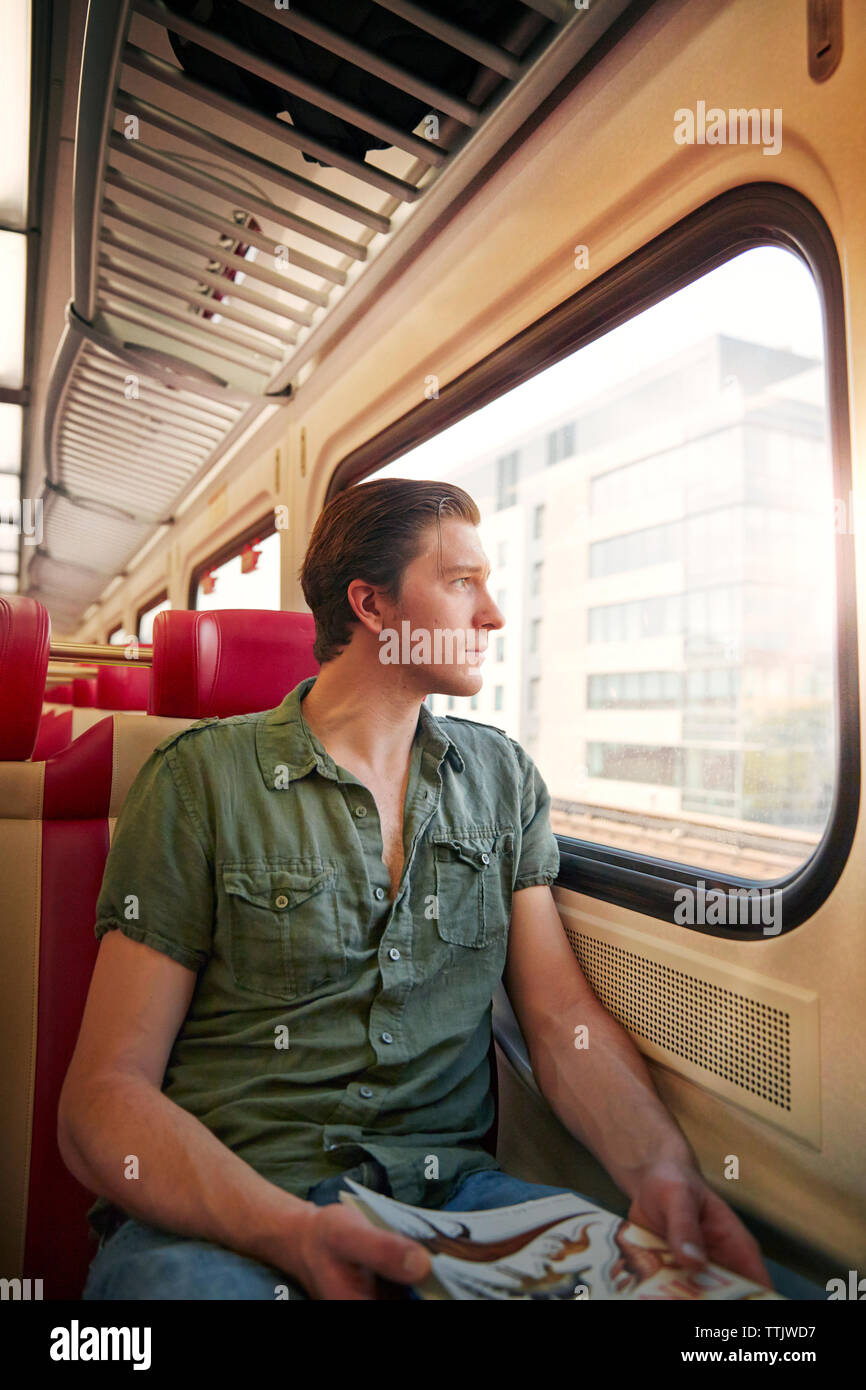 Thoughtful man looking through window while traveling in train Stock Photo