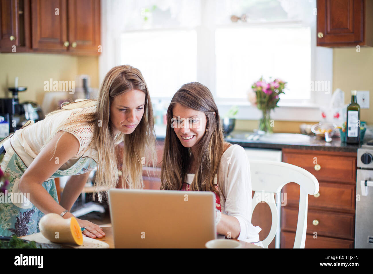 Friends using laptop computer while preparing food at home Stock Photo