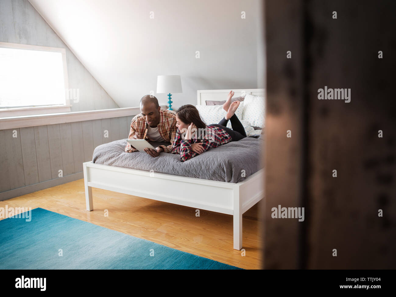 Couple using tablet computer while lying on bed at home Stock Photo