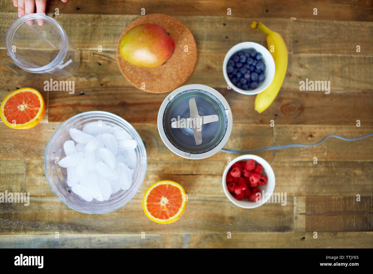 Overhead view of blender with fruits and containers on table Stock Photo