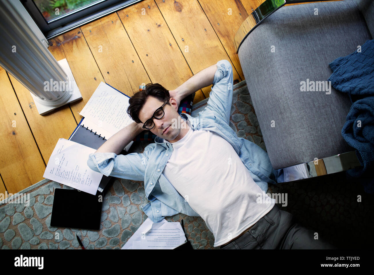 Overhead view of man lying by documents and tablet computer at home Stock Photo