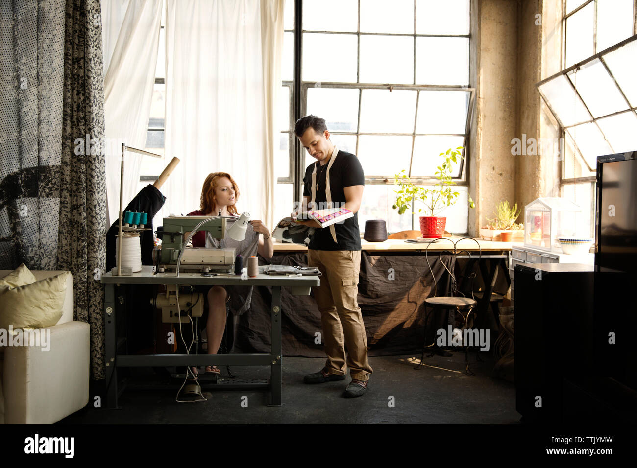 Fashion designers working against windows at workshop Stock Photo