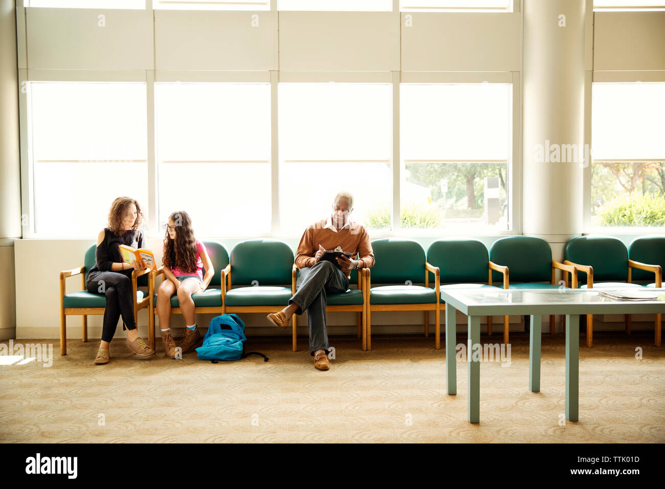Patients sitting on chairs in waiting room Stock Photo Alamy