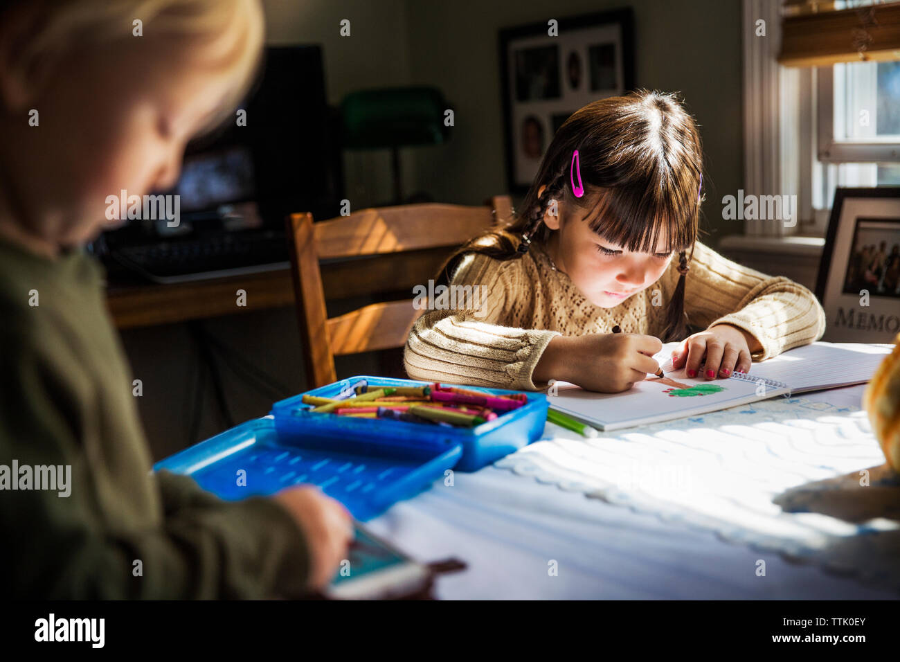 Children drawing while sitting at table Stock Photo