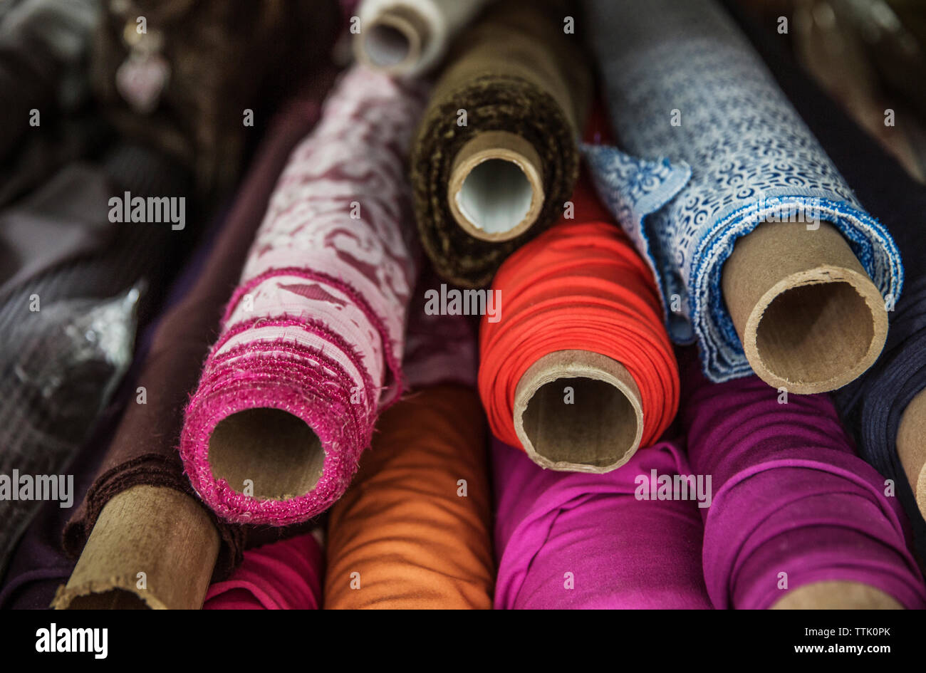 Various rolled fabric swatches on shelf at workshop Stock Photo