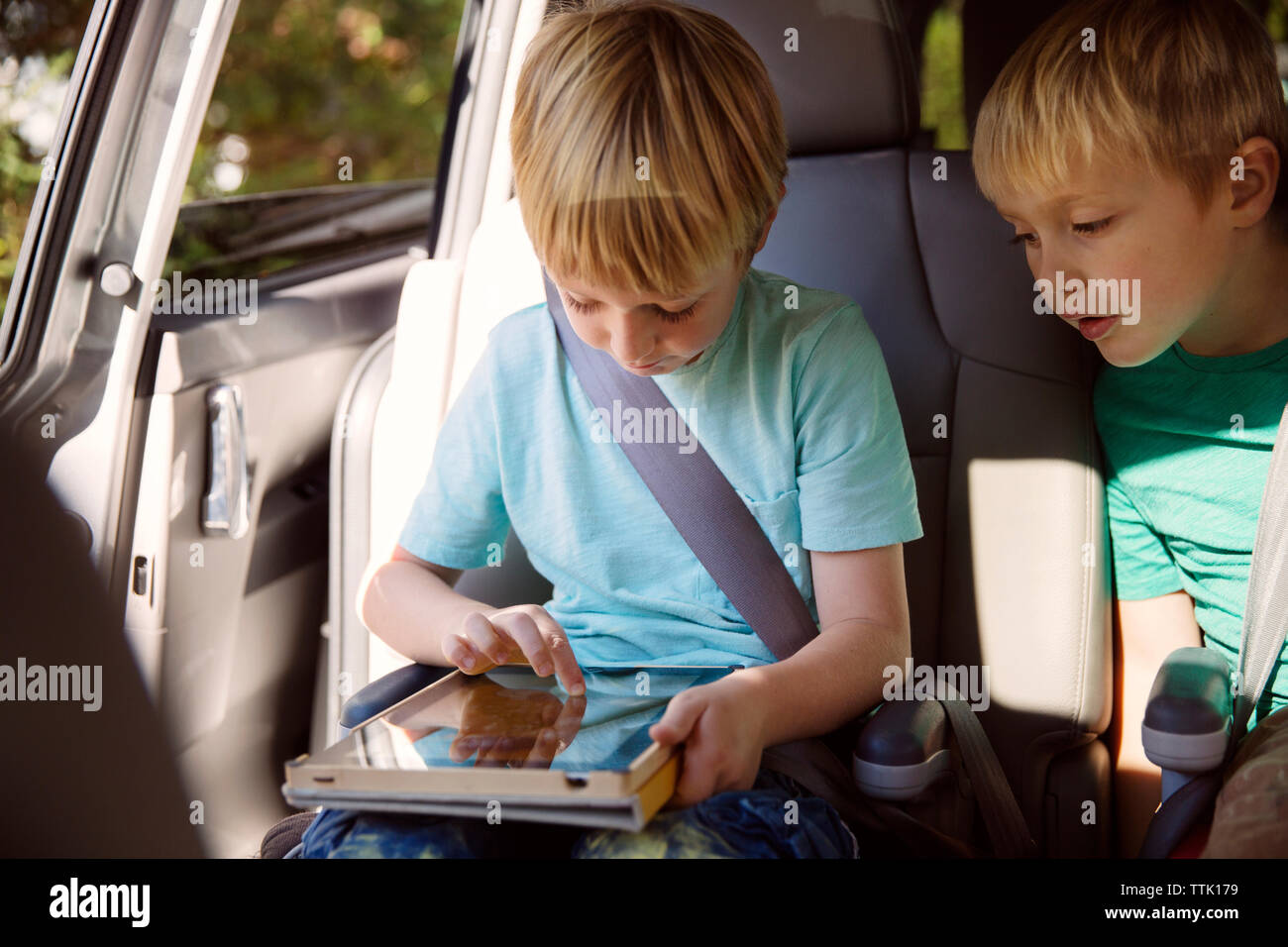 Boy using tablet computer while sitting in car Stock Photo