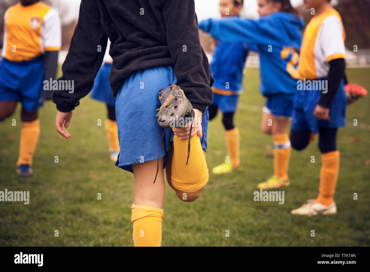 Soccer players stretching legs while warming up on playing field Stock Photo
