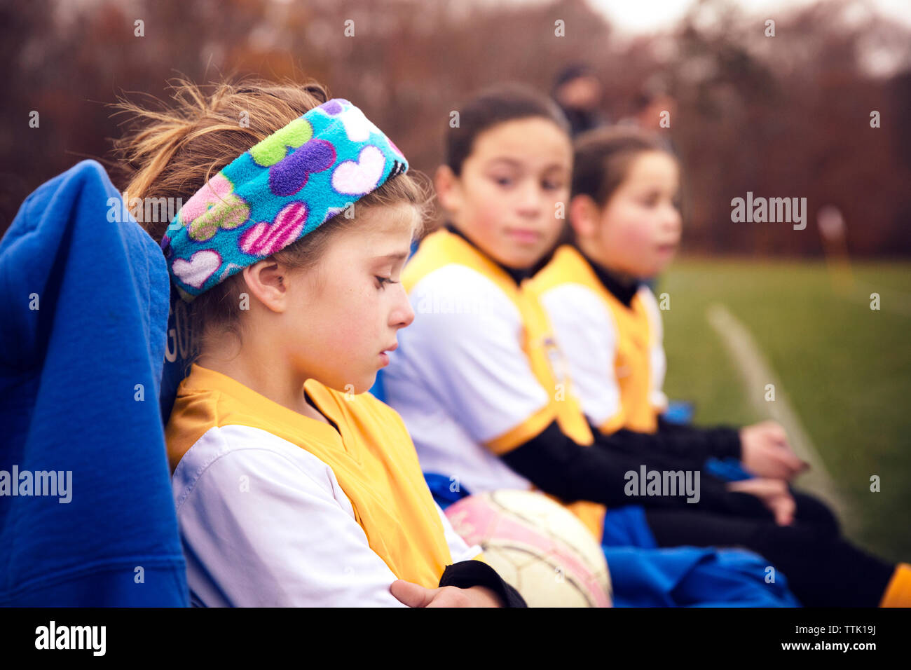 Displeased soccer player sitting with friends at playing field Stock Photo