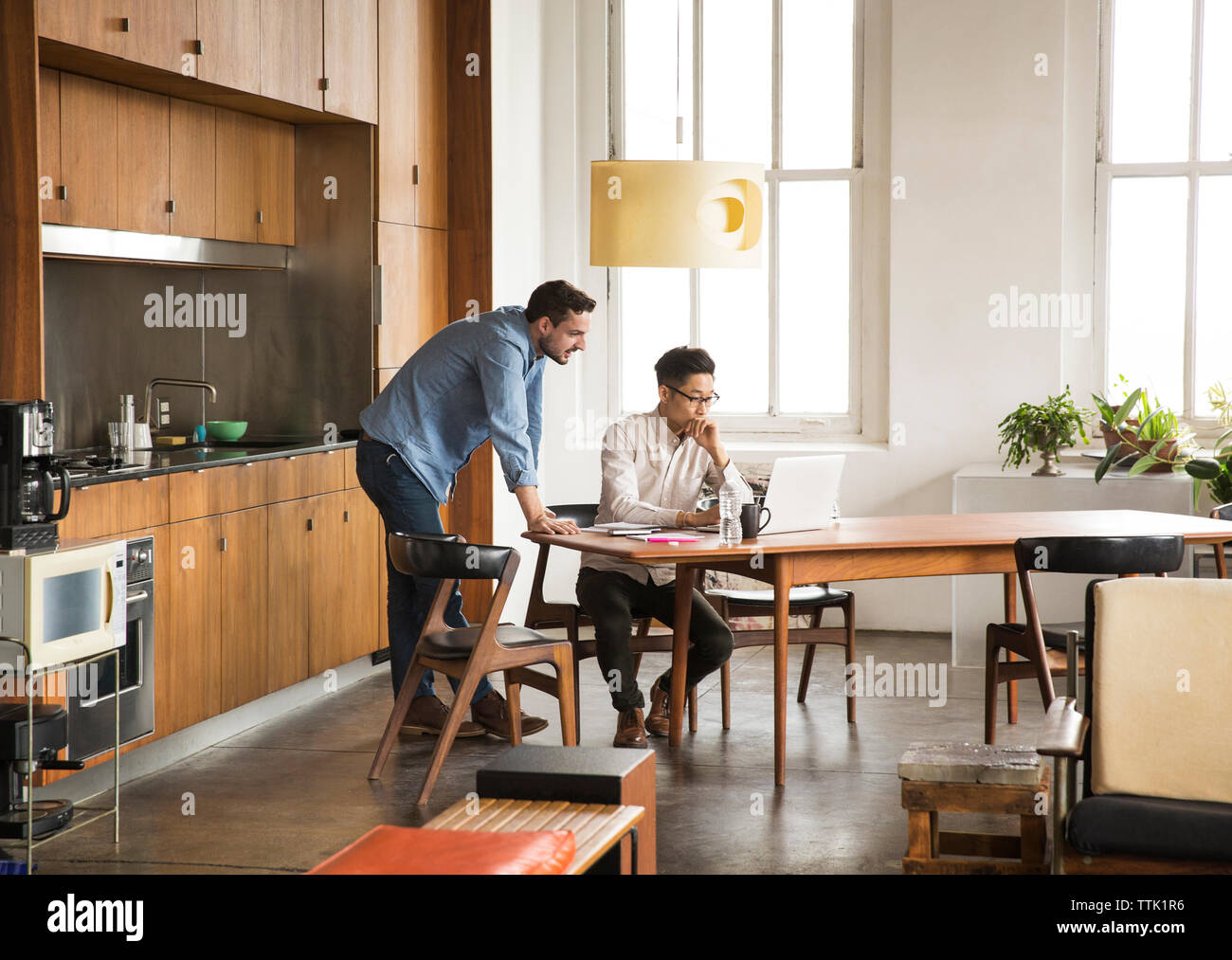 Serious business partners discussing while using laptop computer at creative office Stock Photo
