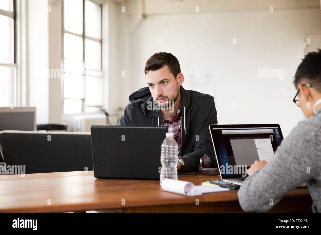 Businessmen using laptop computers at table in creative office Stock Photo