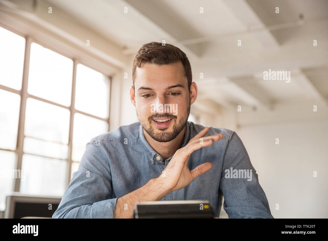 Happy businessman video calling while sitting in office Stock Photo