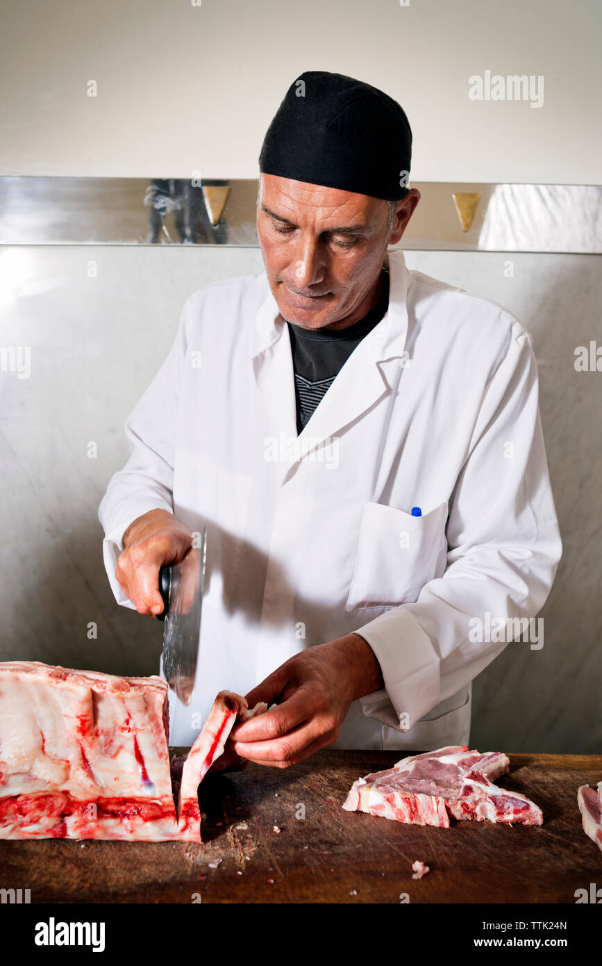 Butcher chopping fresh meat for sale at counter in shop Stock Photo