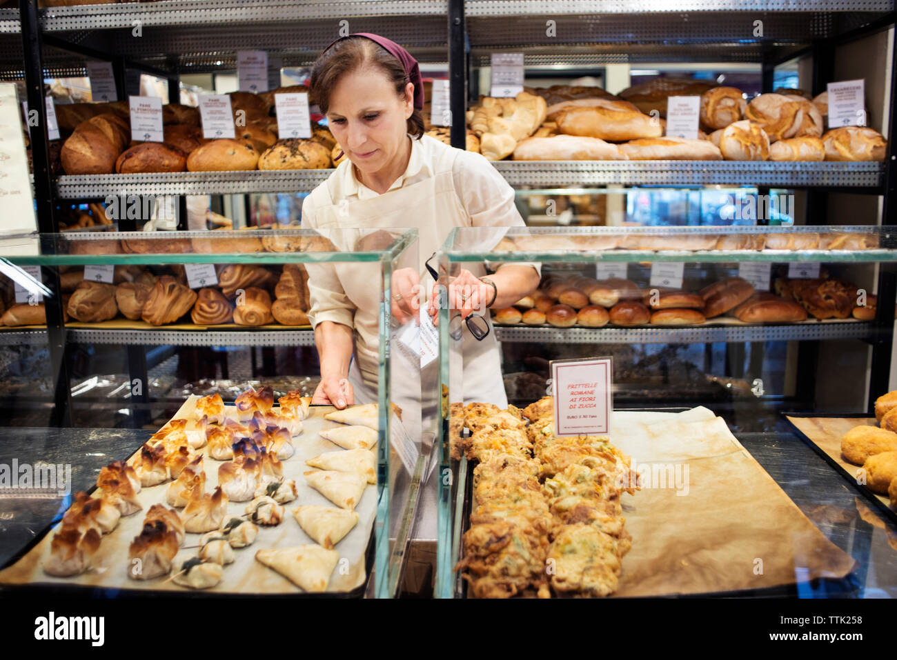 Chef arranging baked food in display cabinet at bakery shop Stock Photo
