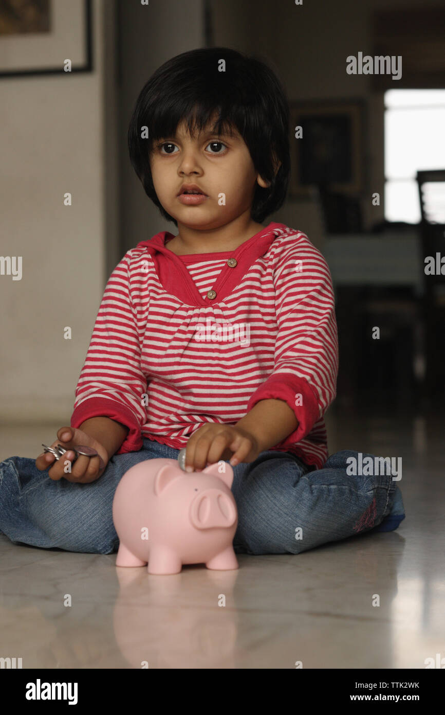 Girl putting a coin into a piggy bank Stock Photo - Alamy