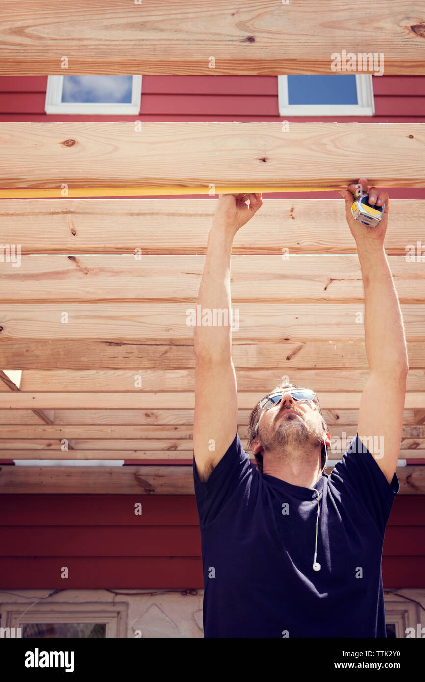 Man measuring plank while standing in yard Stock Photo