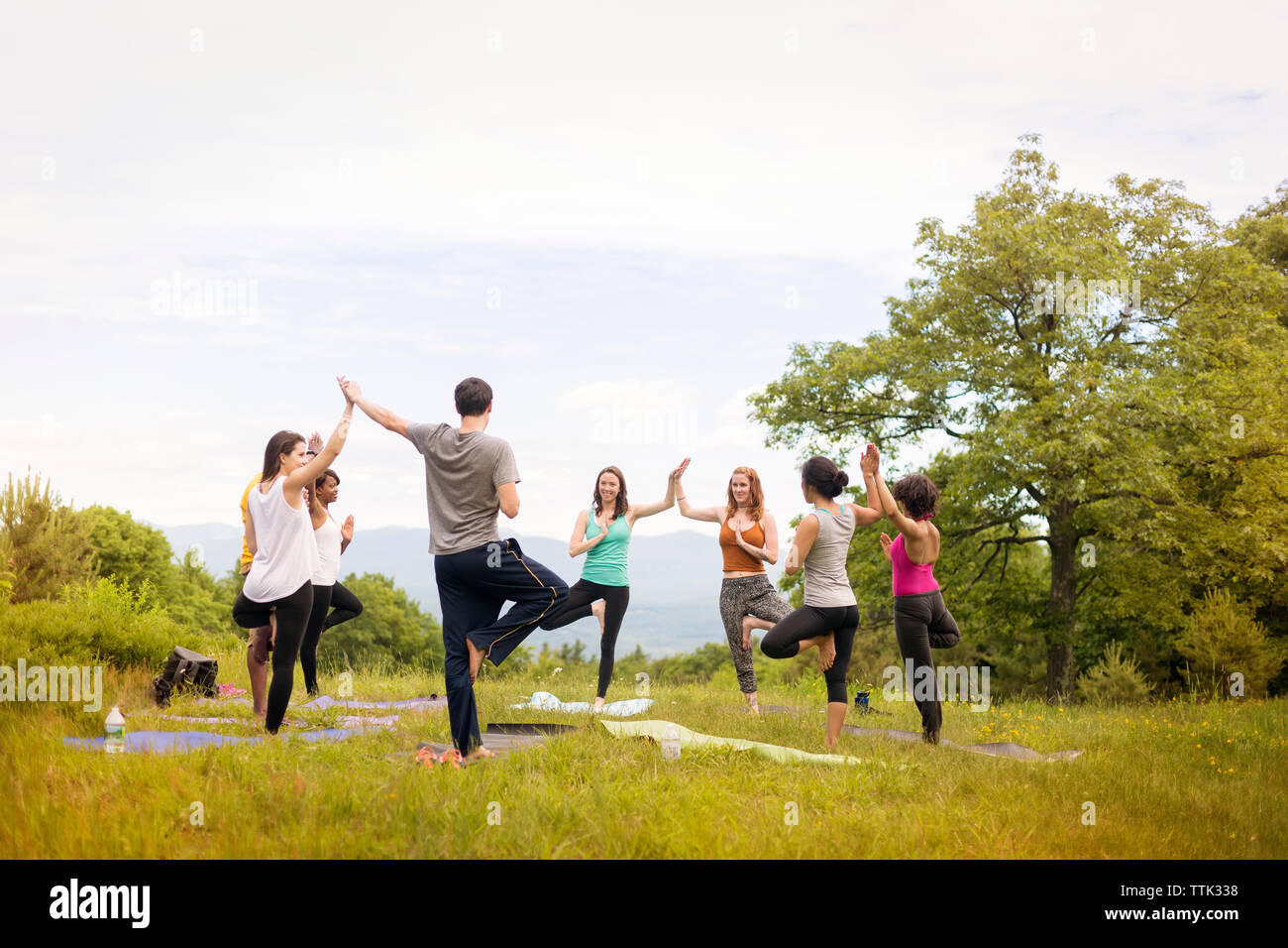 Friends exercising on field against sky Stock Photo