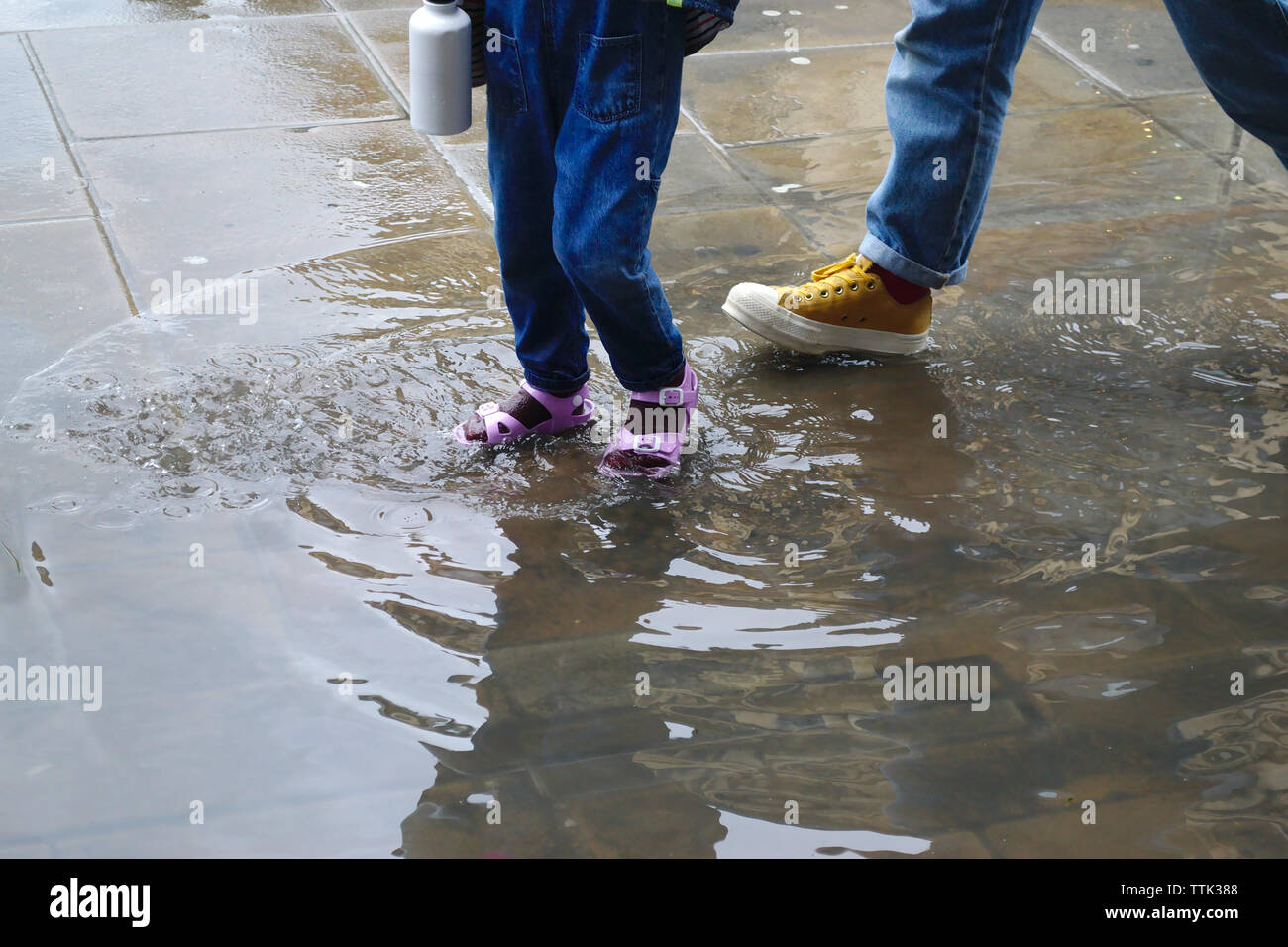 A small baby girl plays in the puddle after heavy rain Stock Photo - Alamy