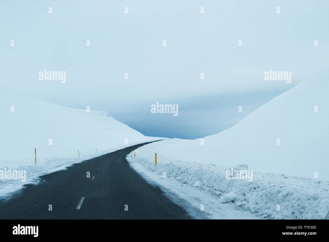Empty country road amidst snowy field against cloudy sky Stock Photo ...