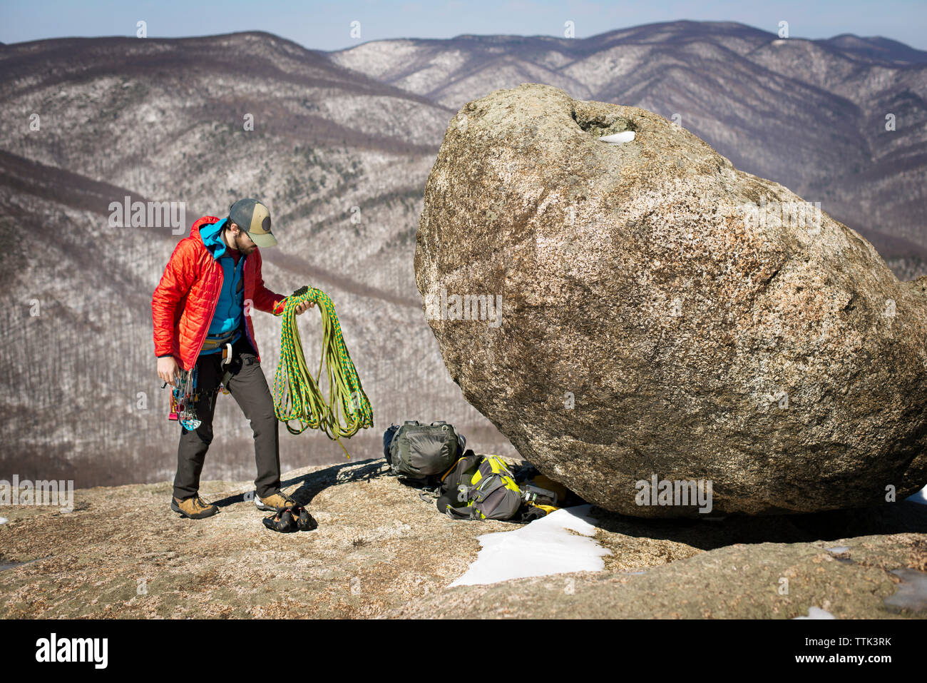 Hiker with climbing rope standing on mountain Stock Photo