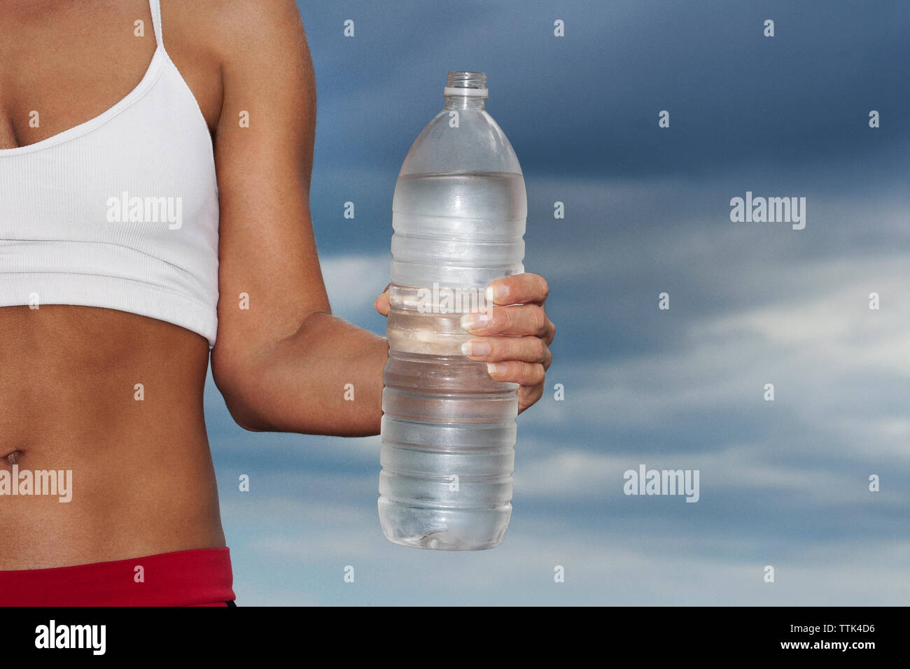 image of woman holding water bottle standing against sky Stock Photo