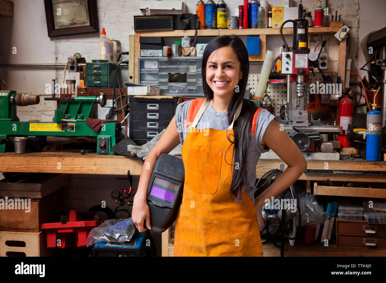 Portrait of happy female mechanic wearing apron in workshop Stock Photo
