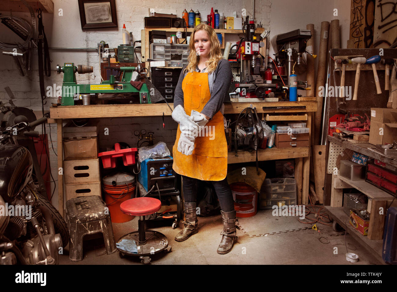 Portrait of confident female mechanic wearing apron in workshop Stock Photo