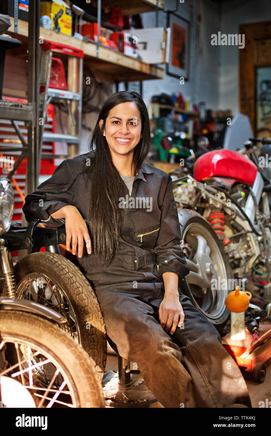 Portrait of happy female mechanic sitting in workshop Stock Photo