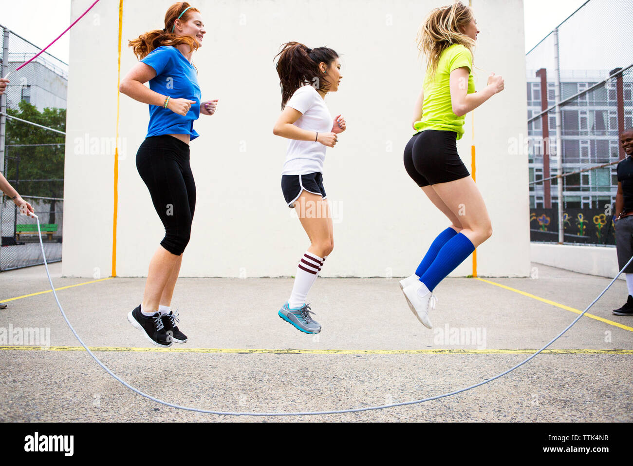 Side view of women performing double Dutch against wall Stock Photo