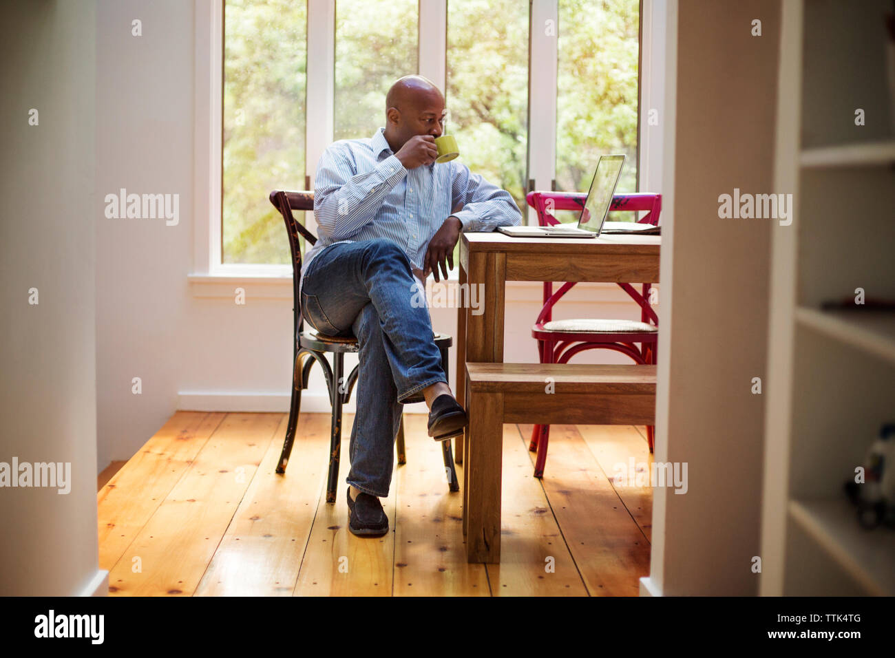 Senior man using laptop while drinking coffee at home Stock Photo