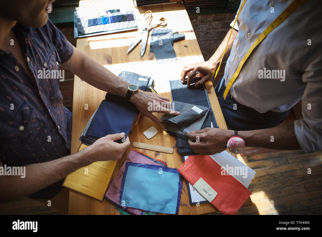 Happy tailor showing fabric swatches to customer Stock Photo
