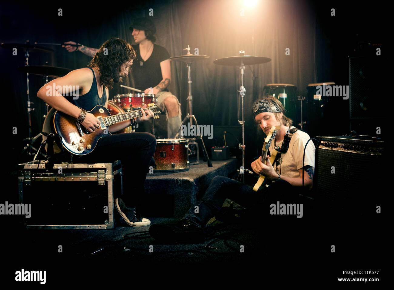 Musical band practicing in illuminated studio Stock Photo