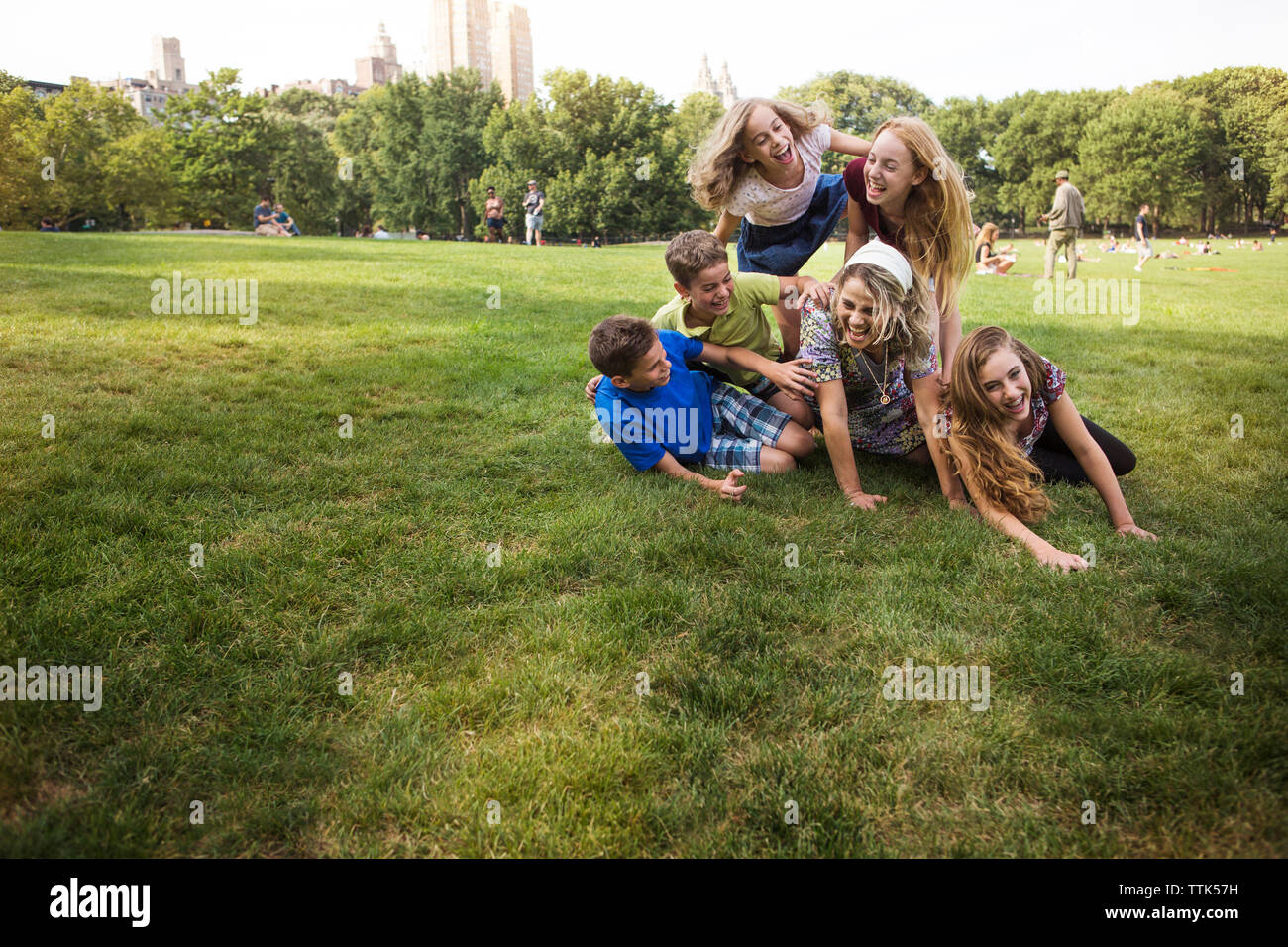 Children enjoying with mother on grassy field at park Stock Photo