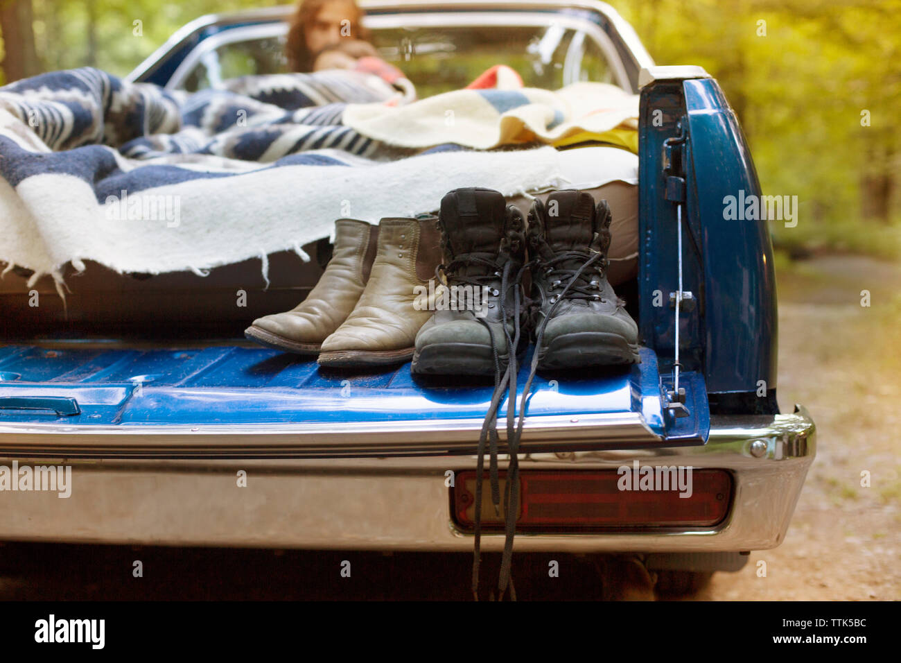 Shoes on pick-up truck with couple relaxing in background Stock Photo
