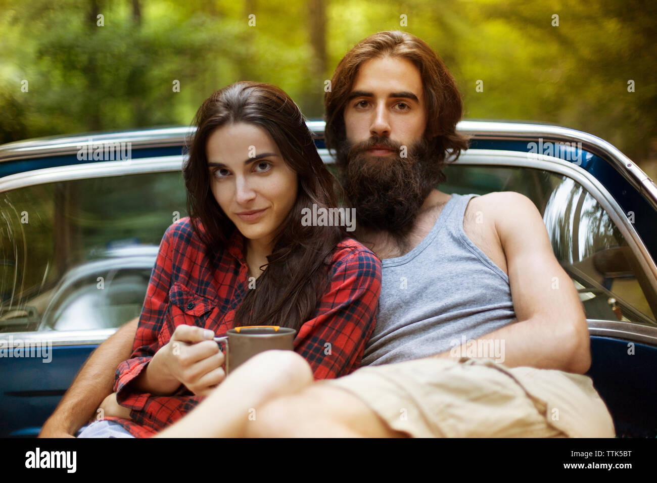 Portrait of confident couple sitting in pick-up truck in forest Stock Photo
