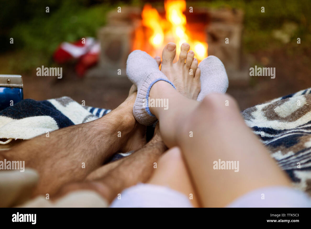 Low section of couple lying in pick-up truck with campfire in background Stock Photo
