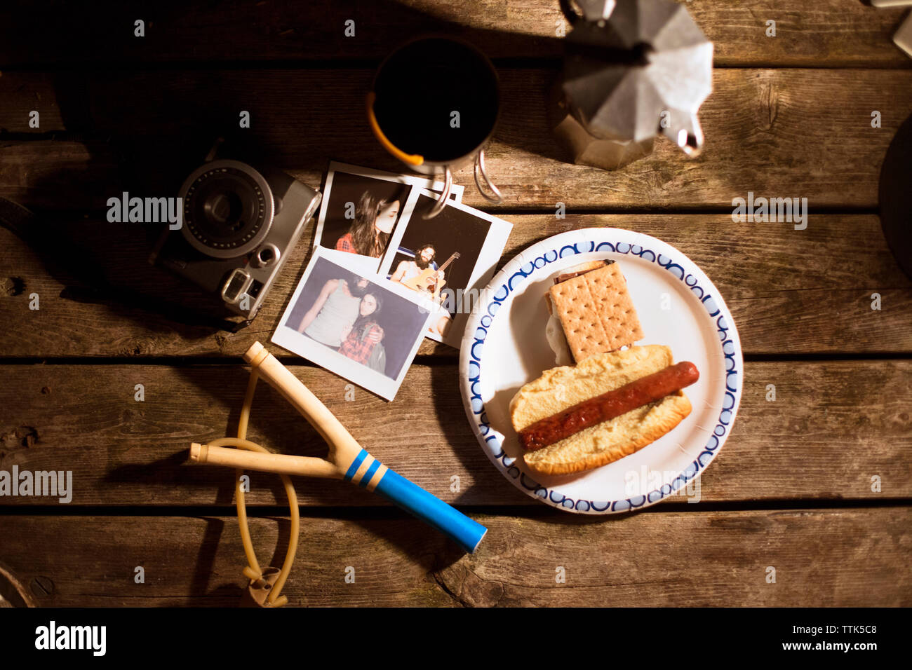 Overhead view of photographs and food with slingshot on wooden table Stock Photo