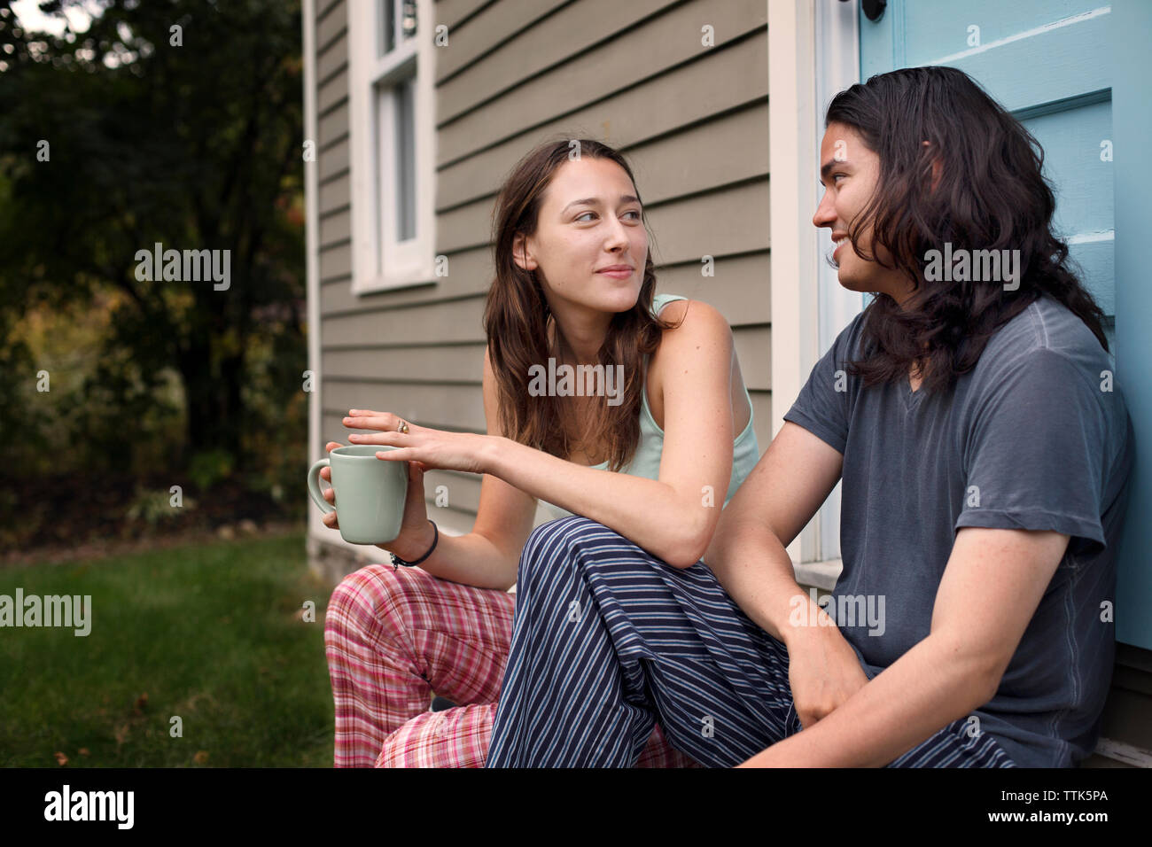 Couple looking at each other while relaxing outside house Stock Photo