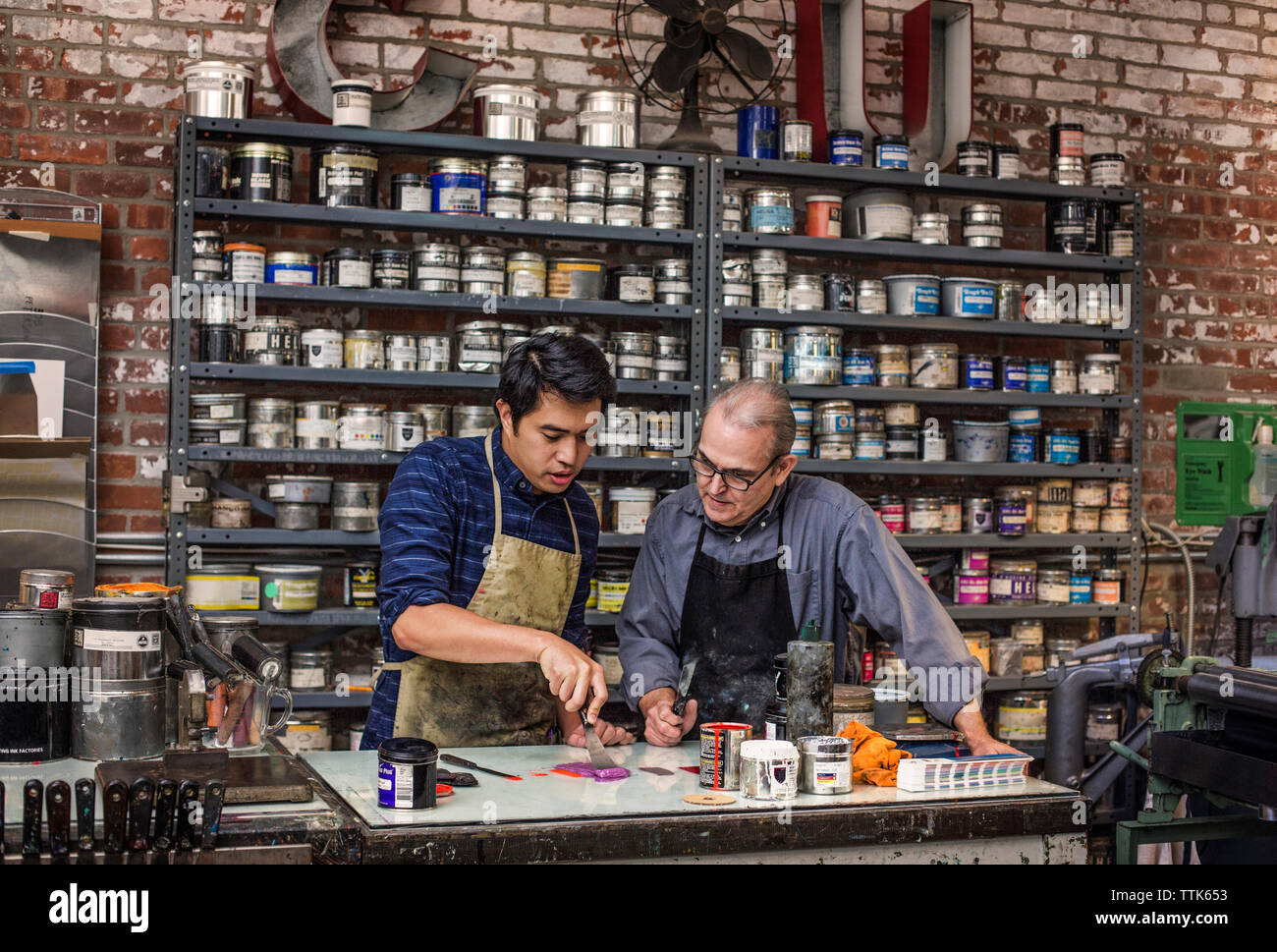 workers mixing colors using ink knife on table at workshop Stock Photo