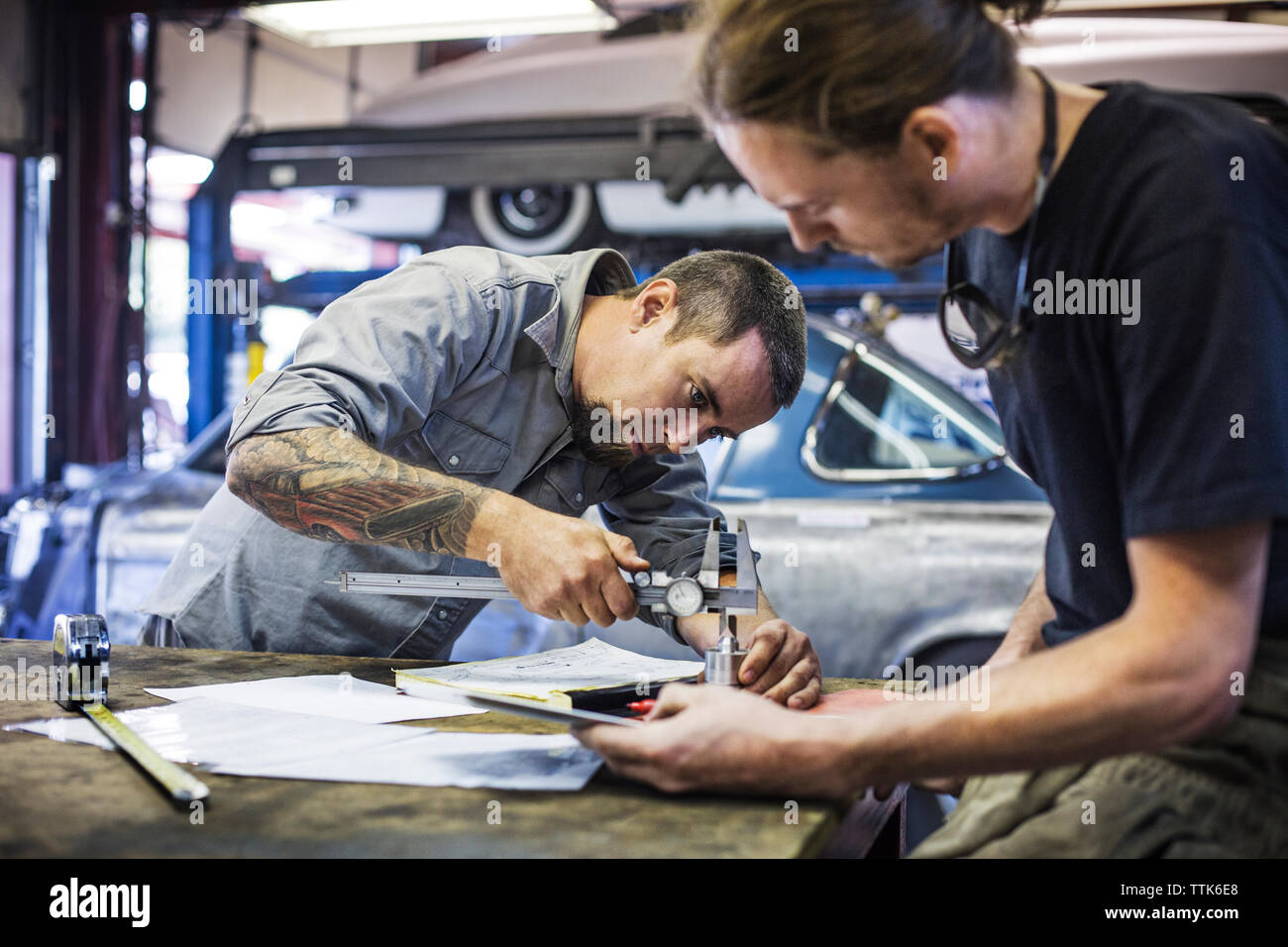 Mechanic using vernier caliper for measuring metal in auto repair shop Stock Photo