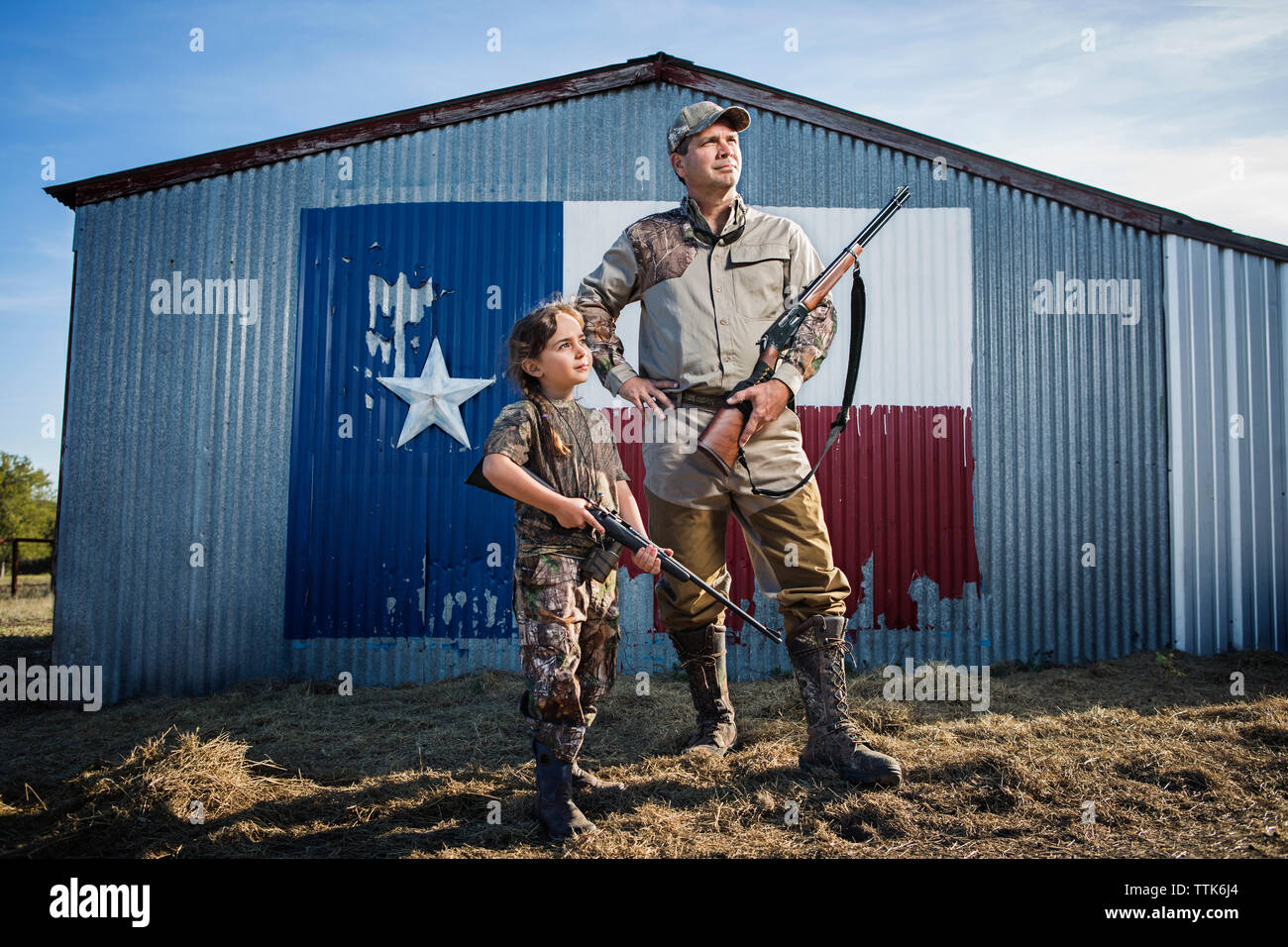 Family holding rifle while standing on field against Texas flag Stock Photo