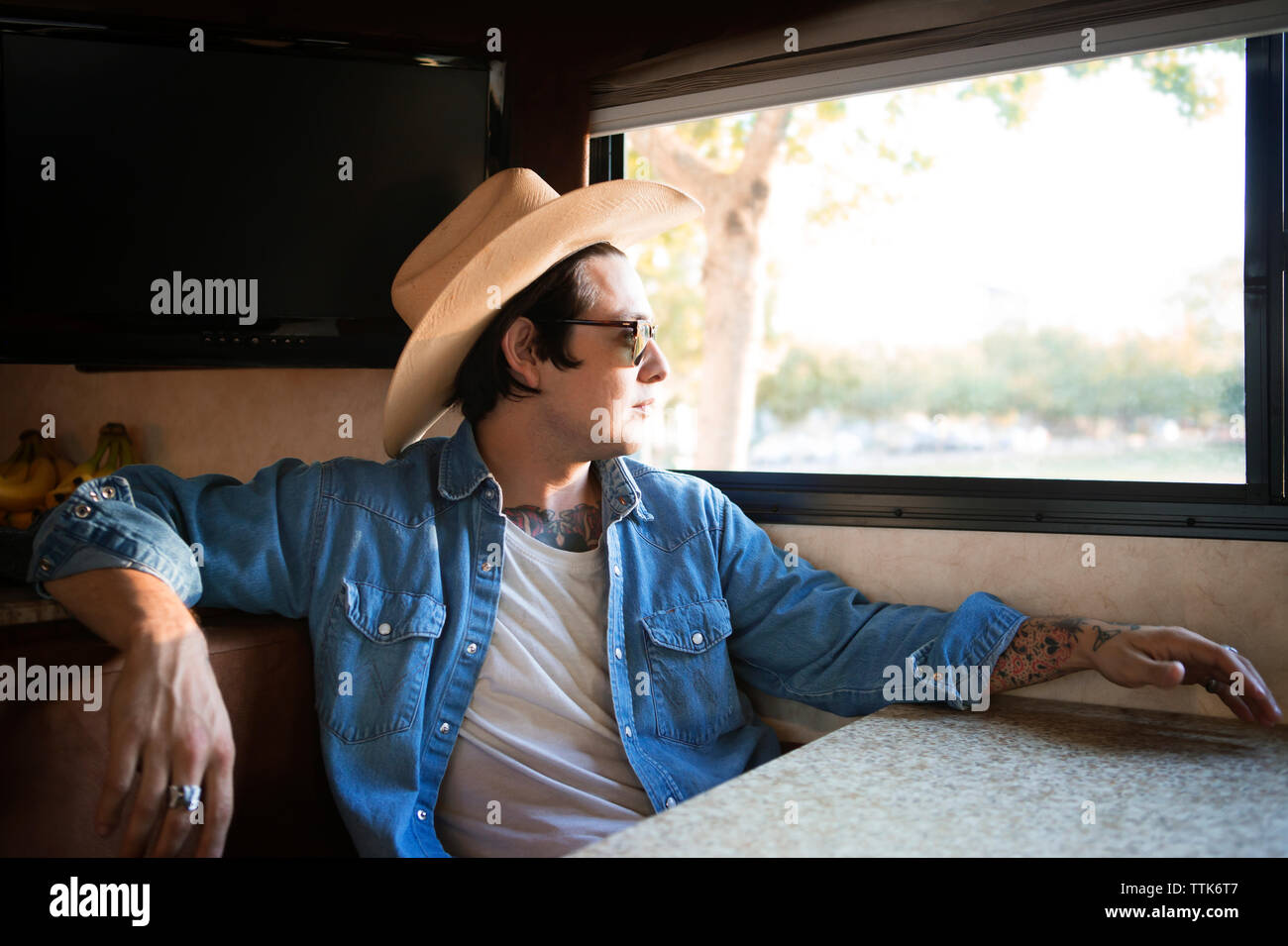 Thoughtful man sitting by window in camper van Stock Photo