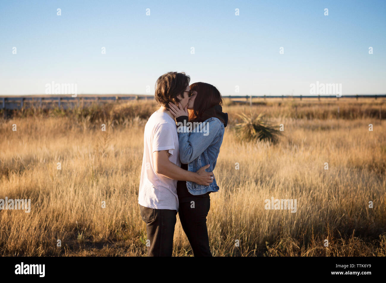 Side view of affectionate couple kissing on field Stock Photo