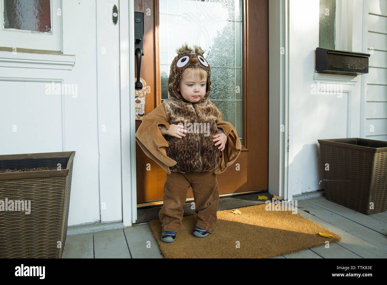 Toddler boy dressed in Halloween costume stands in front of doorway Stock Photo