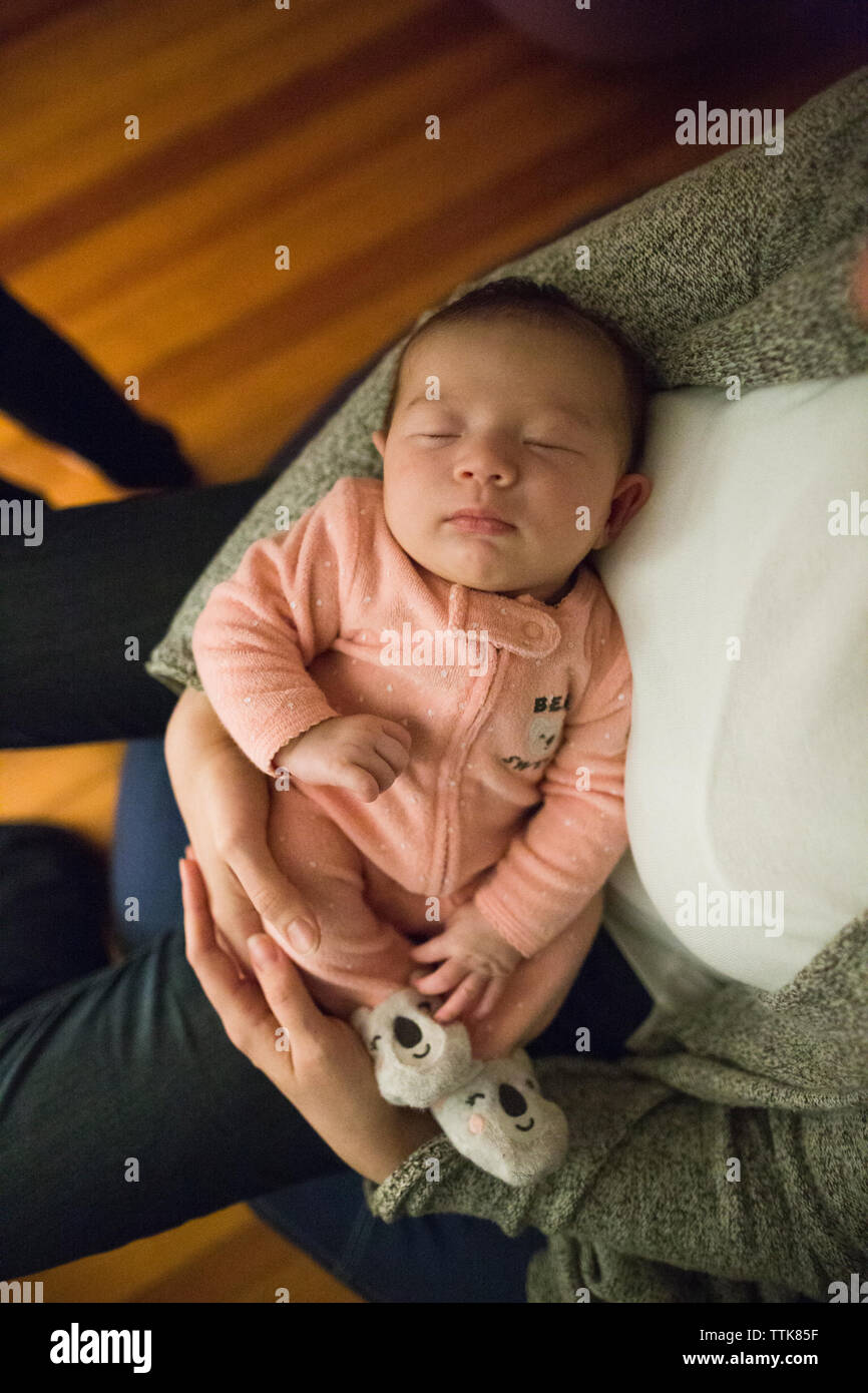 Newborn baby girl sleeps peacefully in mother's arms indoors Stock